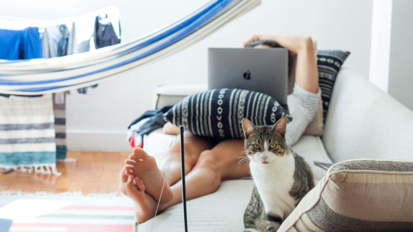 Woman lying on sofa working remotely on laptop